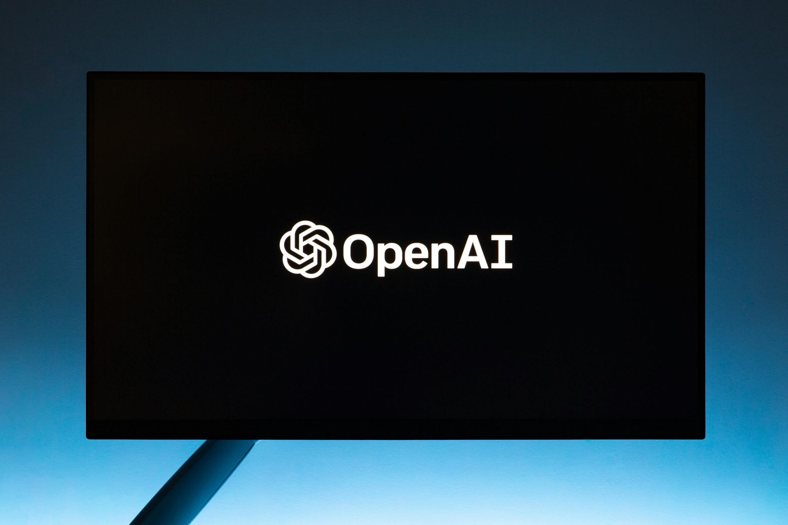 Minimalist display of Codex by OpenAI logo on a screen, set against a gradient blue background.